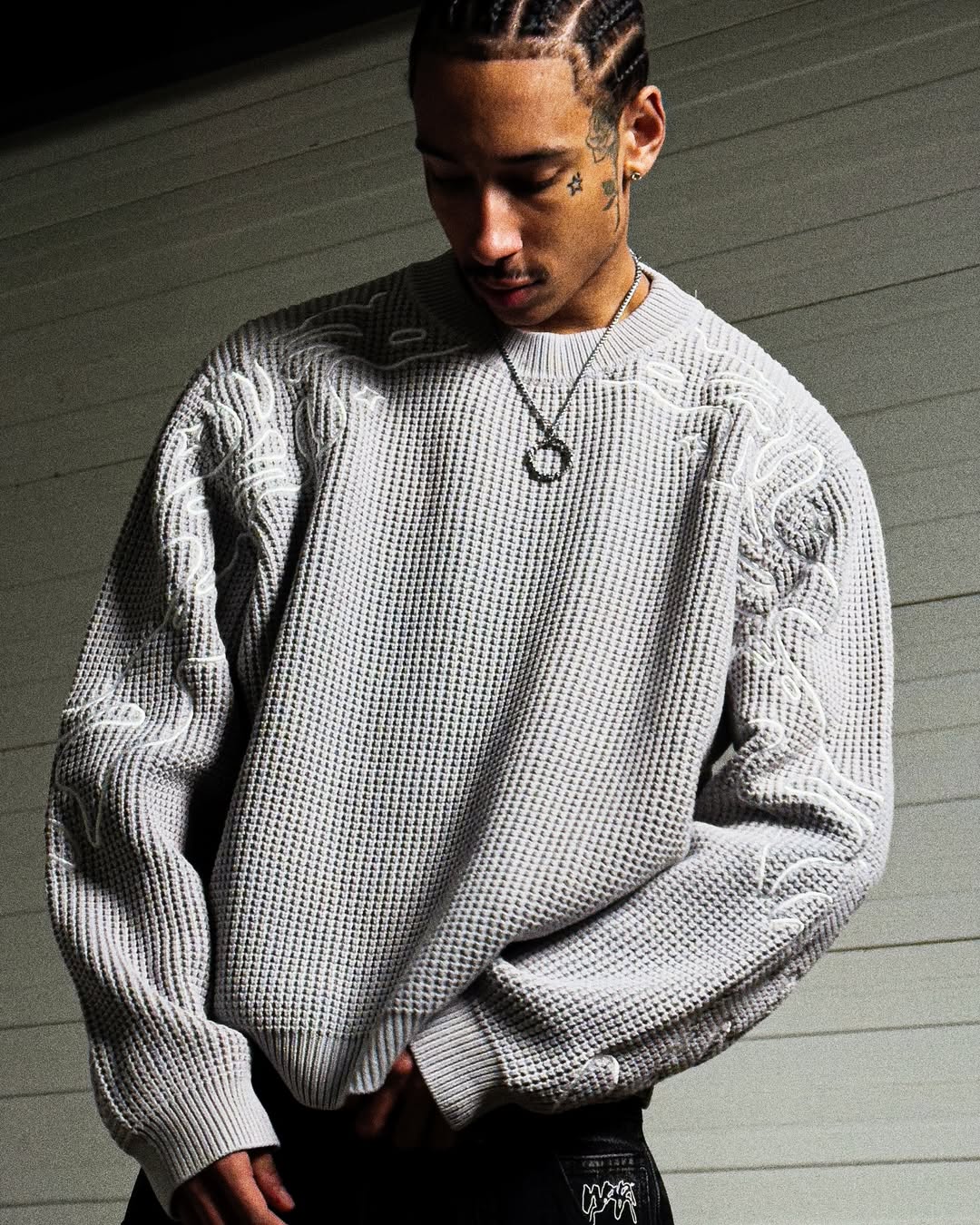 Person wearing a textured gray sweater against a neutral background