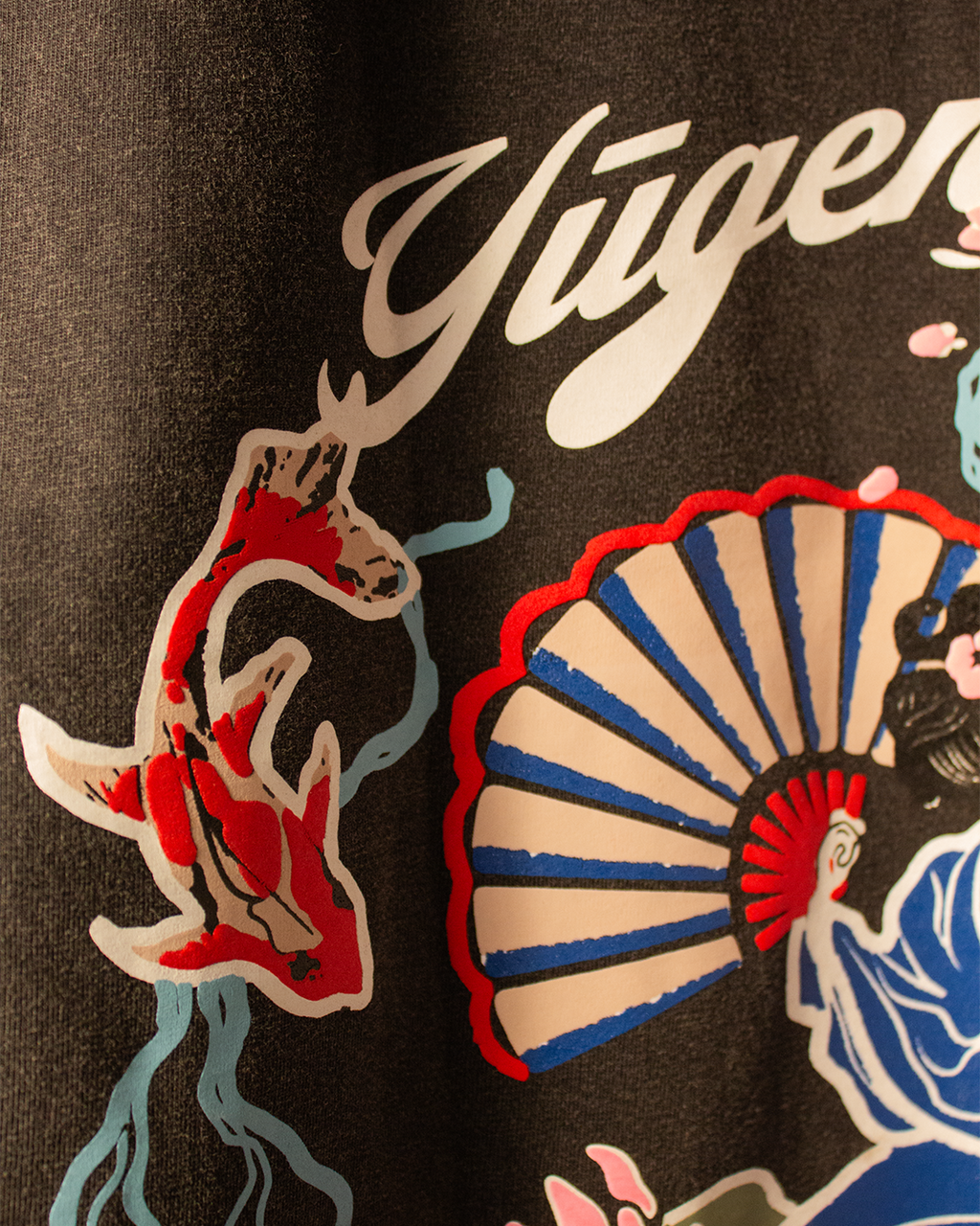 NVRFLD artistic tee with unique design featuring colorful koi fish and a fan graphic on dark fabric
