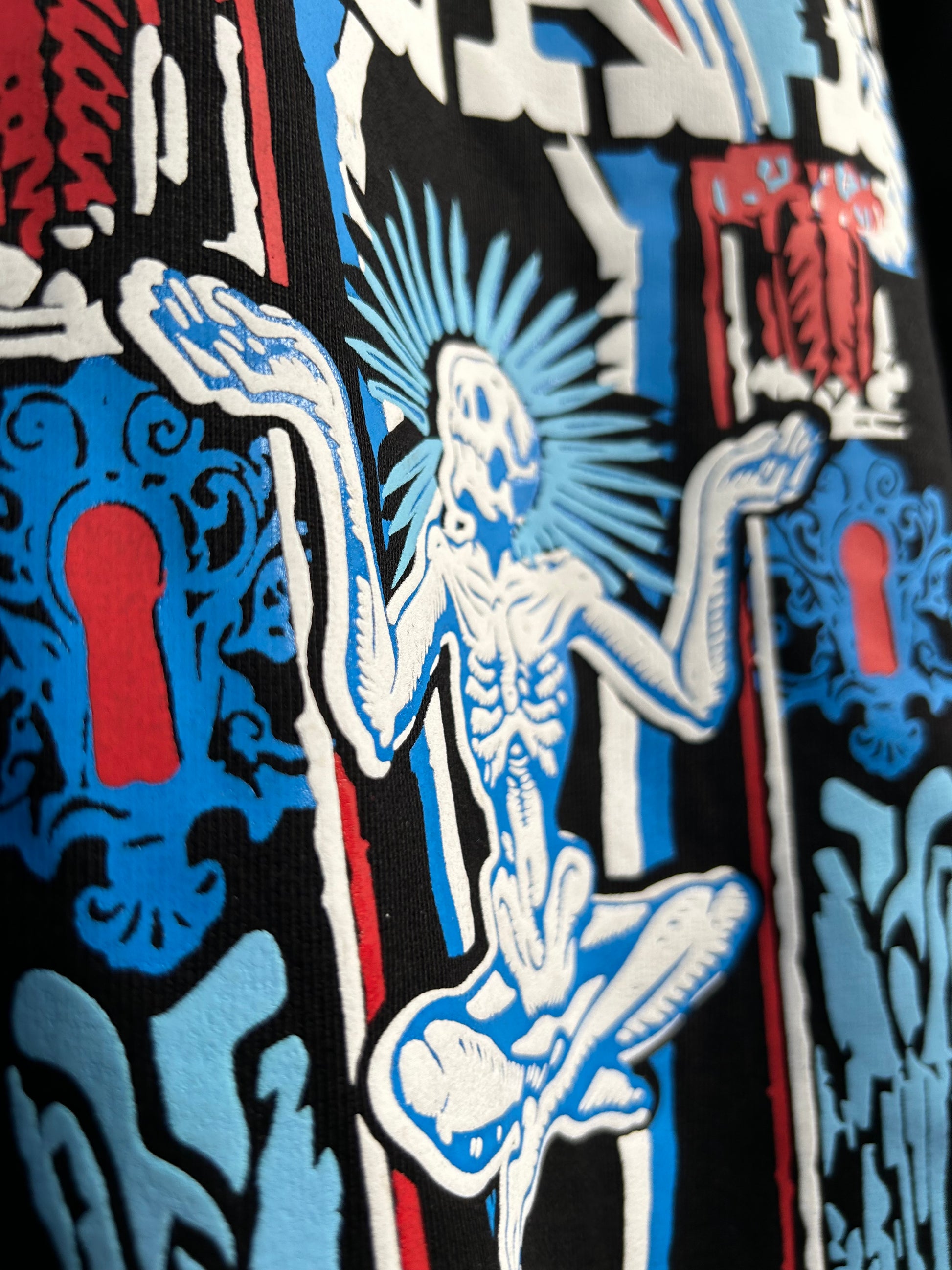Close-up of edgy streetwear hoodies by NVRFLD featuring bold graphic skeleton and keyhole design in red, blue, and white
