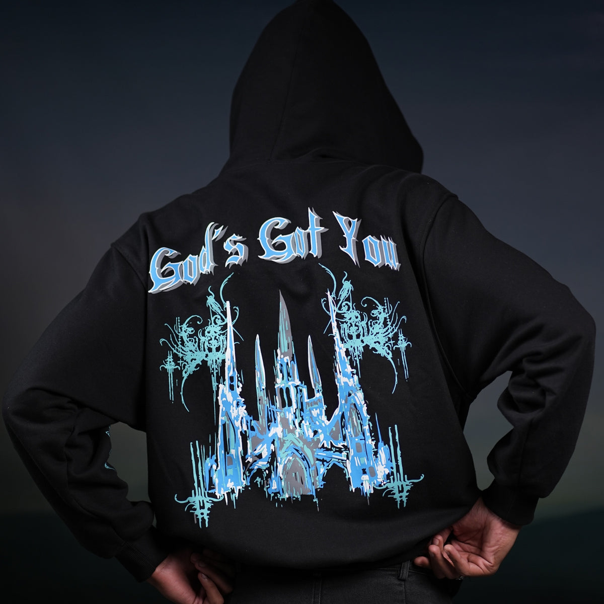Black God hoodie statement piece with blue gothic cathedral graphic and stylized text on back