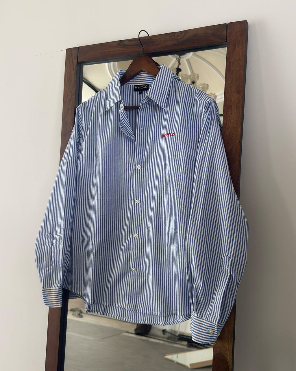 Blue and white striped shirt on a hanger in front of a mirror