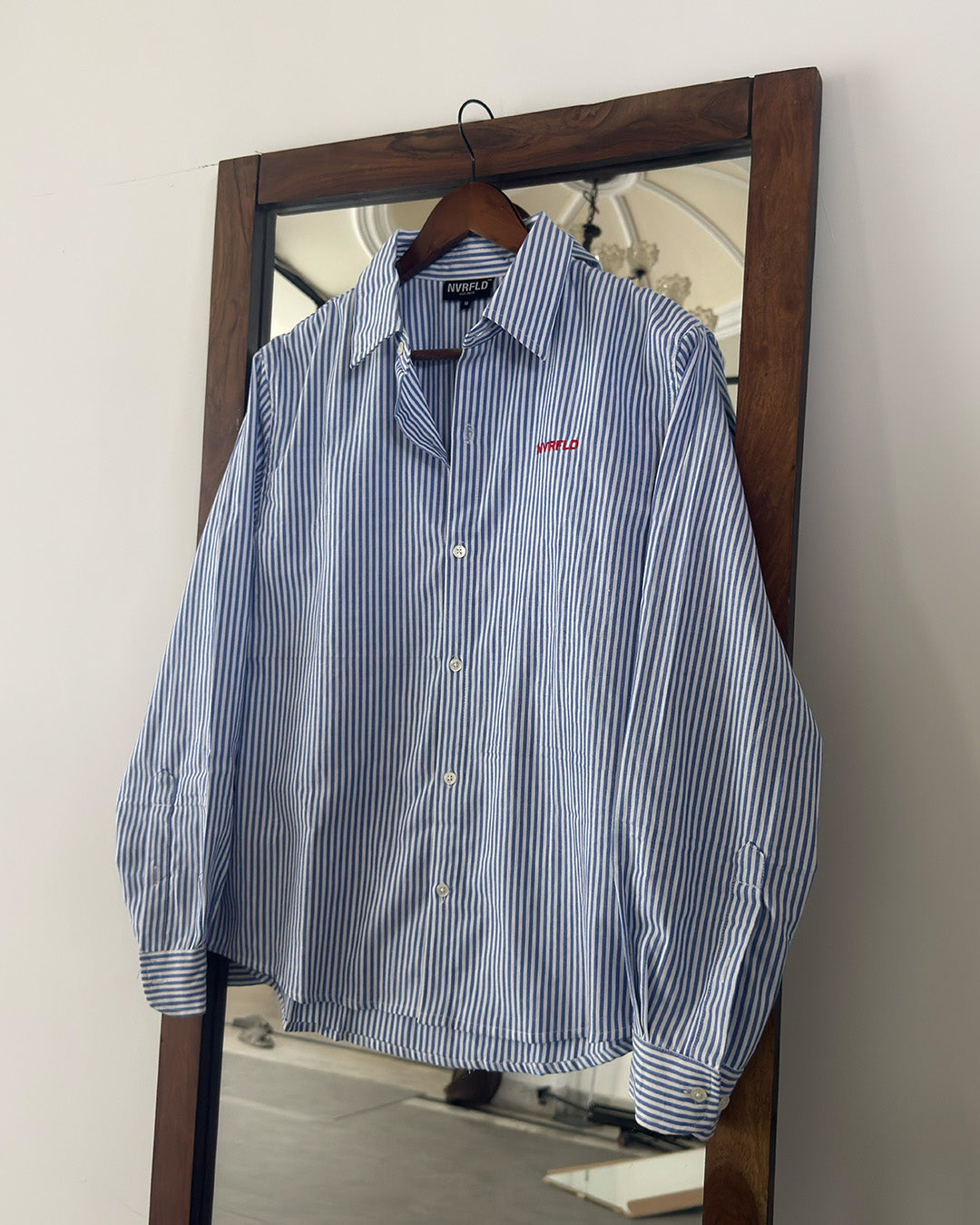 Blue and white striped shirt on a hanger in front of a mirror
